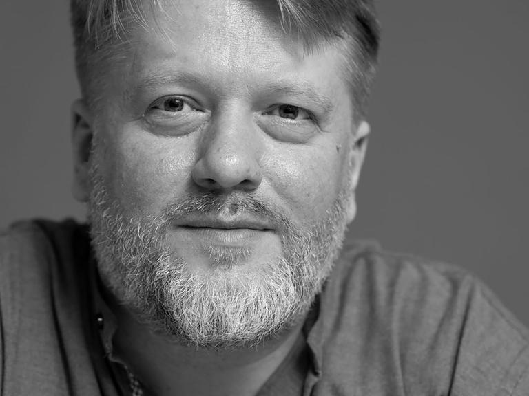 Schwarz-Weiß Portrait von Georg Genoux, der freundlich in die Kamera schaut