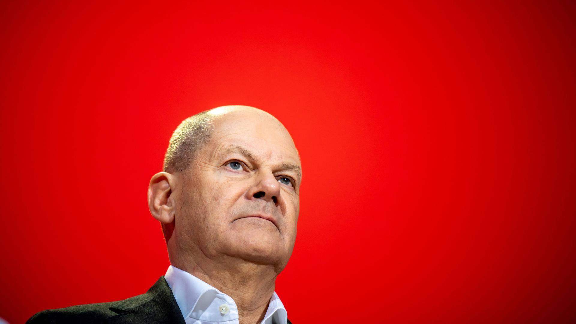 Bundeskanzler Olaf Scholz vor einem roten Hintergrund