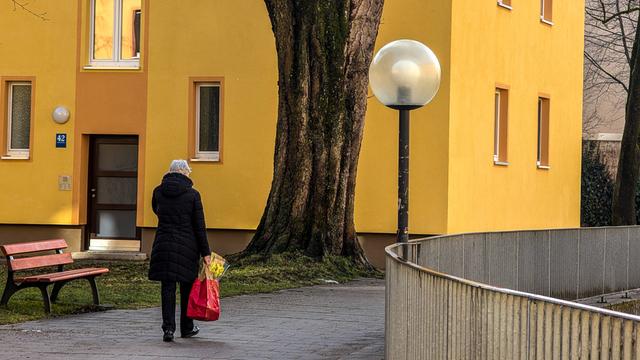 Eine alte Frau läuft alleine durch ein städtisches Wohnviertel. Sie trägt eine Einkaufstüte in der Hand. (Symbolbild)