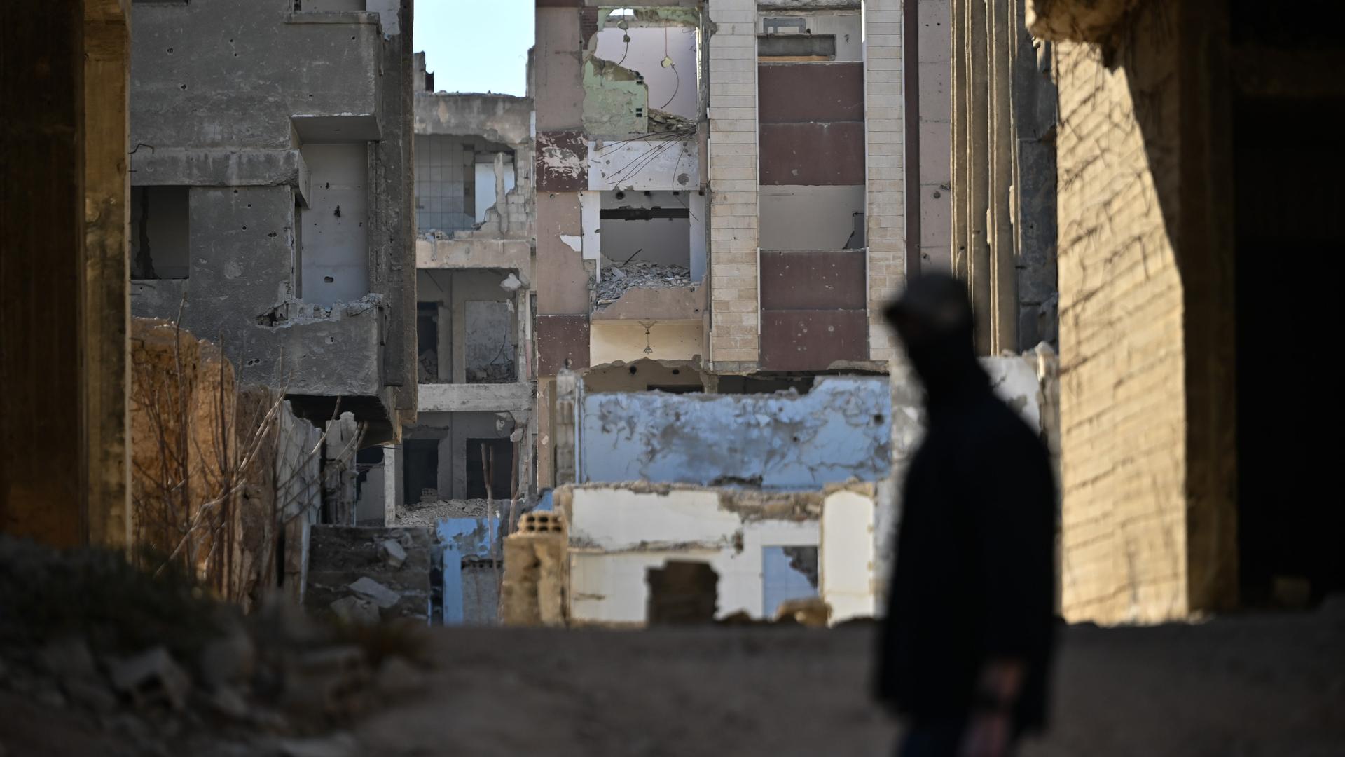 Ein Sicherheitsmann geht im Stadtteil Dschubar in Syrien vor Ruinen. 