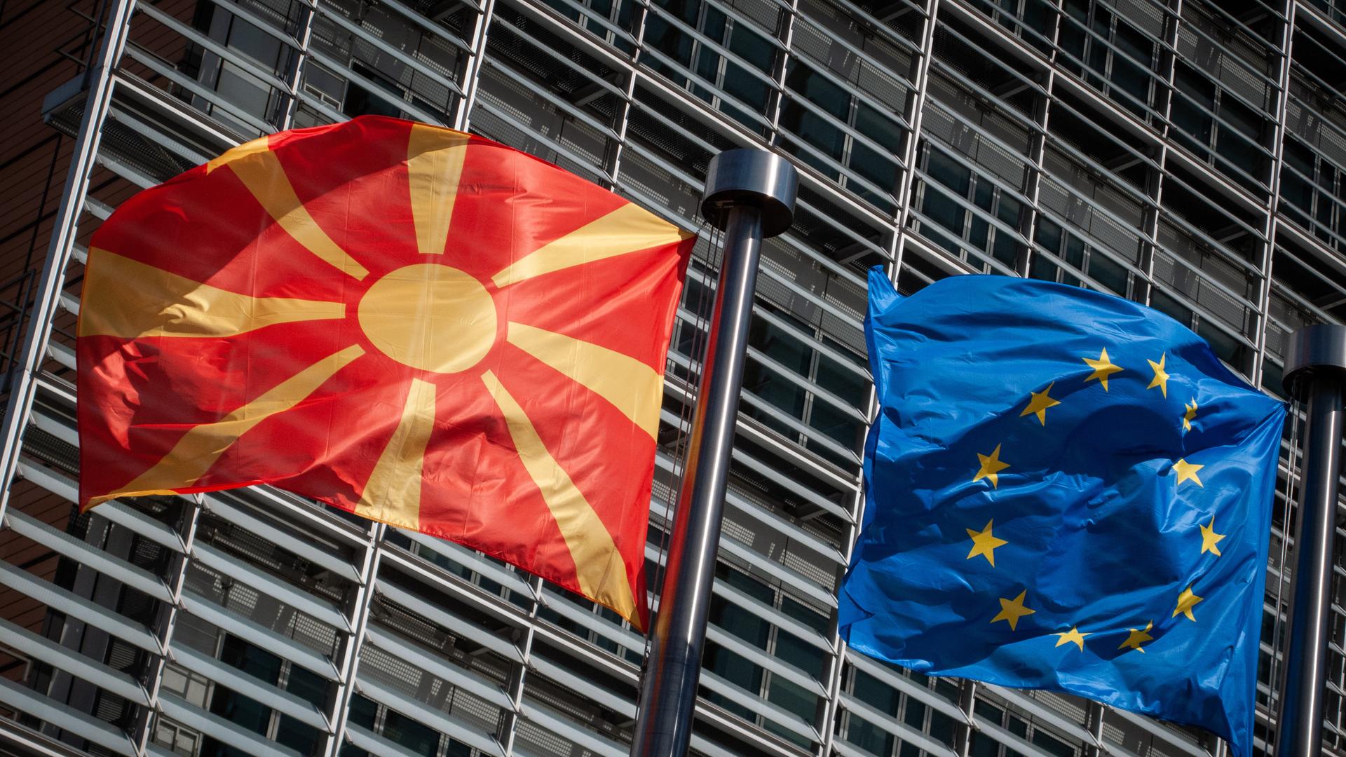 Eine Flagge von Nordmazedonien weht neben einer EU-Flagge im Wind vor dem Berlaymont-Gebäude der EU-Kommission. 