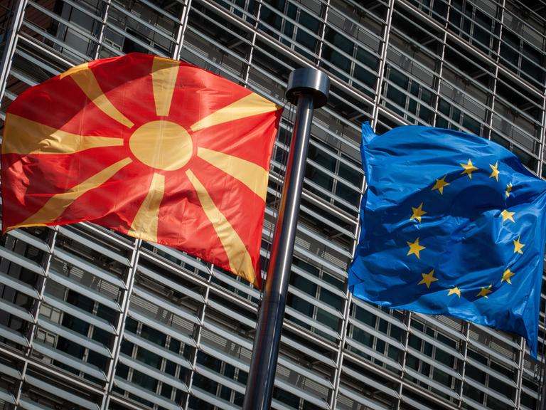 Eine Flagge von Nordmazedonien weht neben einer EU-Flagge im Wind vor dem Berlaymont-Gebäude der EU-Kommission. 