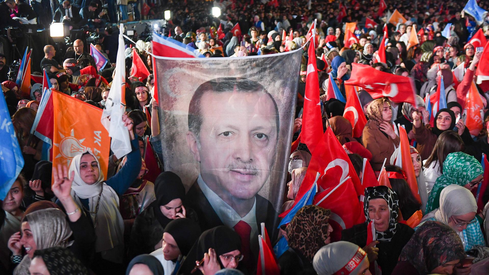 Unterstützer des Präsidenten Recep Tayyip Erdogan halten Tranzparent mit einem Foto von ihm hoch und schwenken türkische Fahnen.