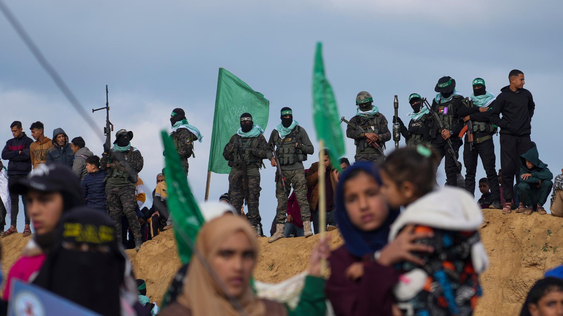 Palästinenser beobachten, wie Hamas-Kämpfer Stellung beziehen, bevor sie die Leichen von vier israelischen Geiseln am 20.02.2025 an das Rote Kreuz in Khan Younis im südlichen Gazastreifen übergeben.