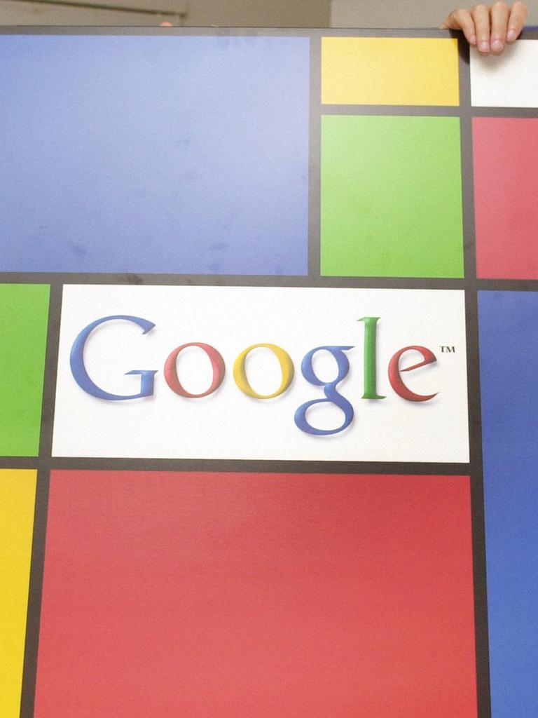 Zwei etwa 30-jährige Männer halten lachend eine farbige Tafel mit dem Firmenlogo "Google" hoch.