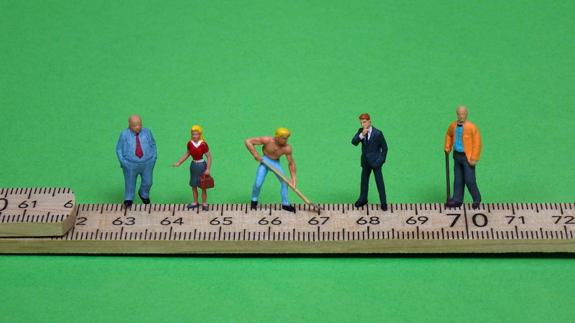 Figuren auf einem Zollstock. Ihr Standort markiert das jeweilige Rentenalter. Figuren auf einem Zollstock. Ihr Standort markiert das jeweilige Rentenalter.