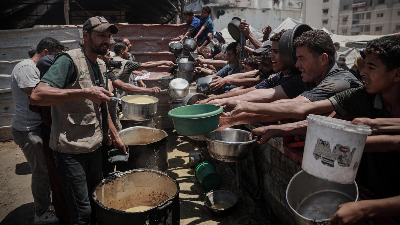 Palästinenser im Gazastreifen drängen sich an einer Essensausgabe und halten leere Schüsseln in der Hand.