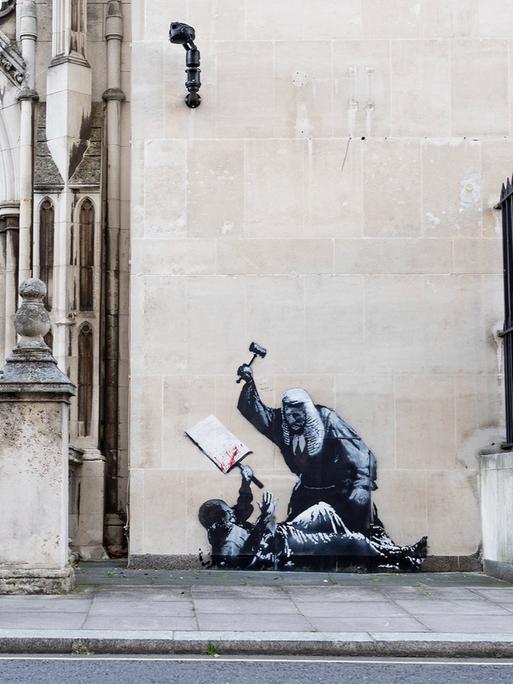 Das Foto soll ein Kunstwerk von Banksy zeigen. Es zeigt einen Richter, der einen Demonstranten im Royal Courts of Justice in London mit einem Hammer schlägt. Das Foto soll ein Kunstwerk von Banksy zeigen. Es zeigt einen Richter, der einen Demonstranten im Royal Courts of Justice in London mit einem Hammer schlägt.