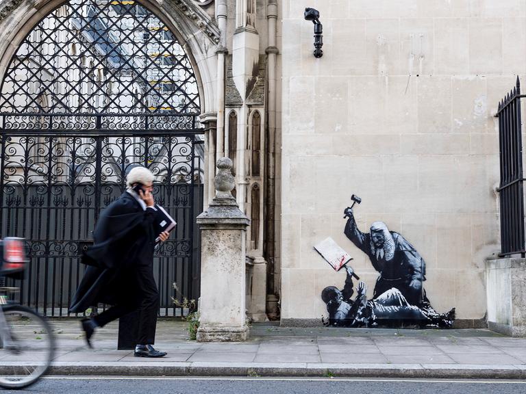 Das Foto soll ein Kunstwerk von Banksy zeigen. Es zeigt einen Richter, der einen Demonstranten im Royal Courts of Justice in London mit einem Hammer schlägt. Das Foto soll ein Kunstwerk von Banksy zeigen. Es zeigt einen Richter, der einen Demonstranten im Royal Courts of Justice in London mit einem Hammer schlägt.