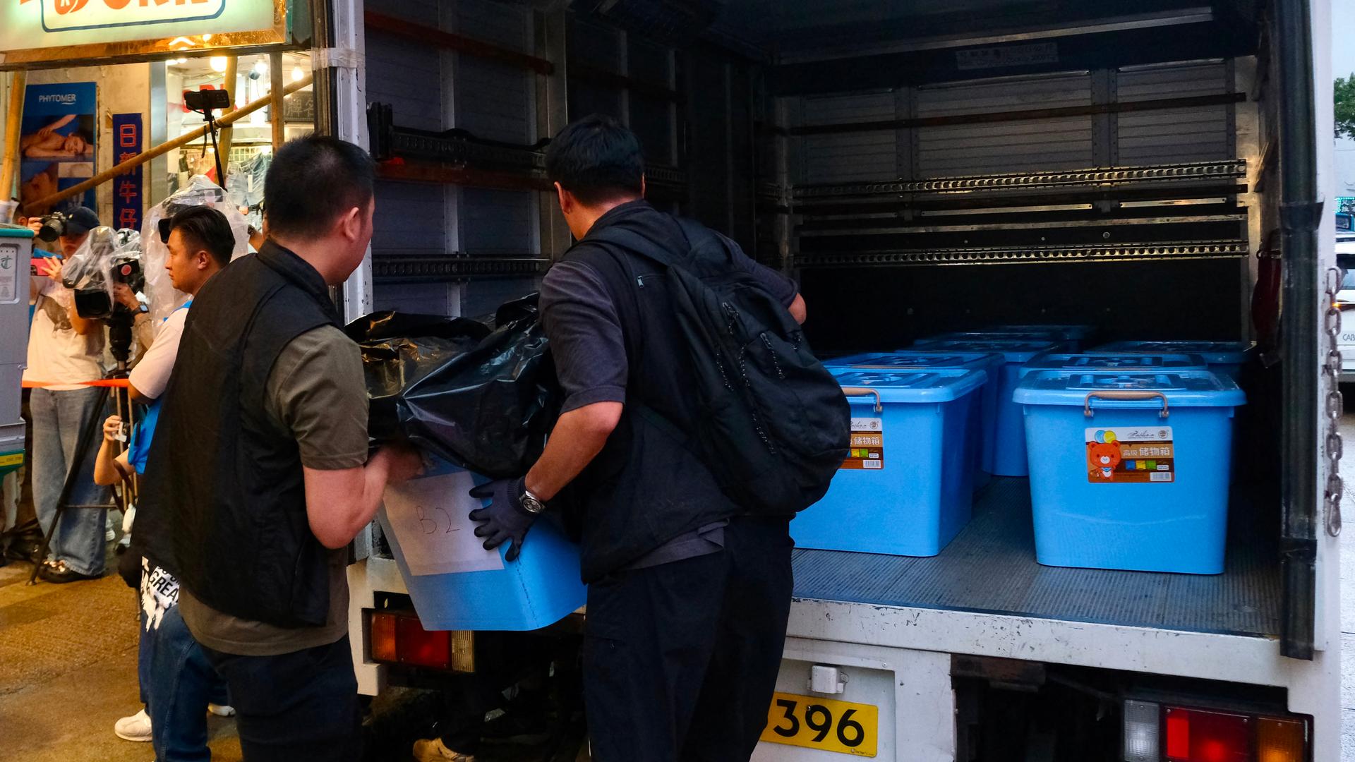 Polizisten laden beschlagnahmtes Material aus einem Buchladen in Hongkong in ihr Auto. Polizisten laden beschlagnahmtes Material aus einem Buchladen in Hongkong in ihr Auto.