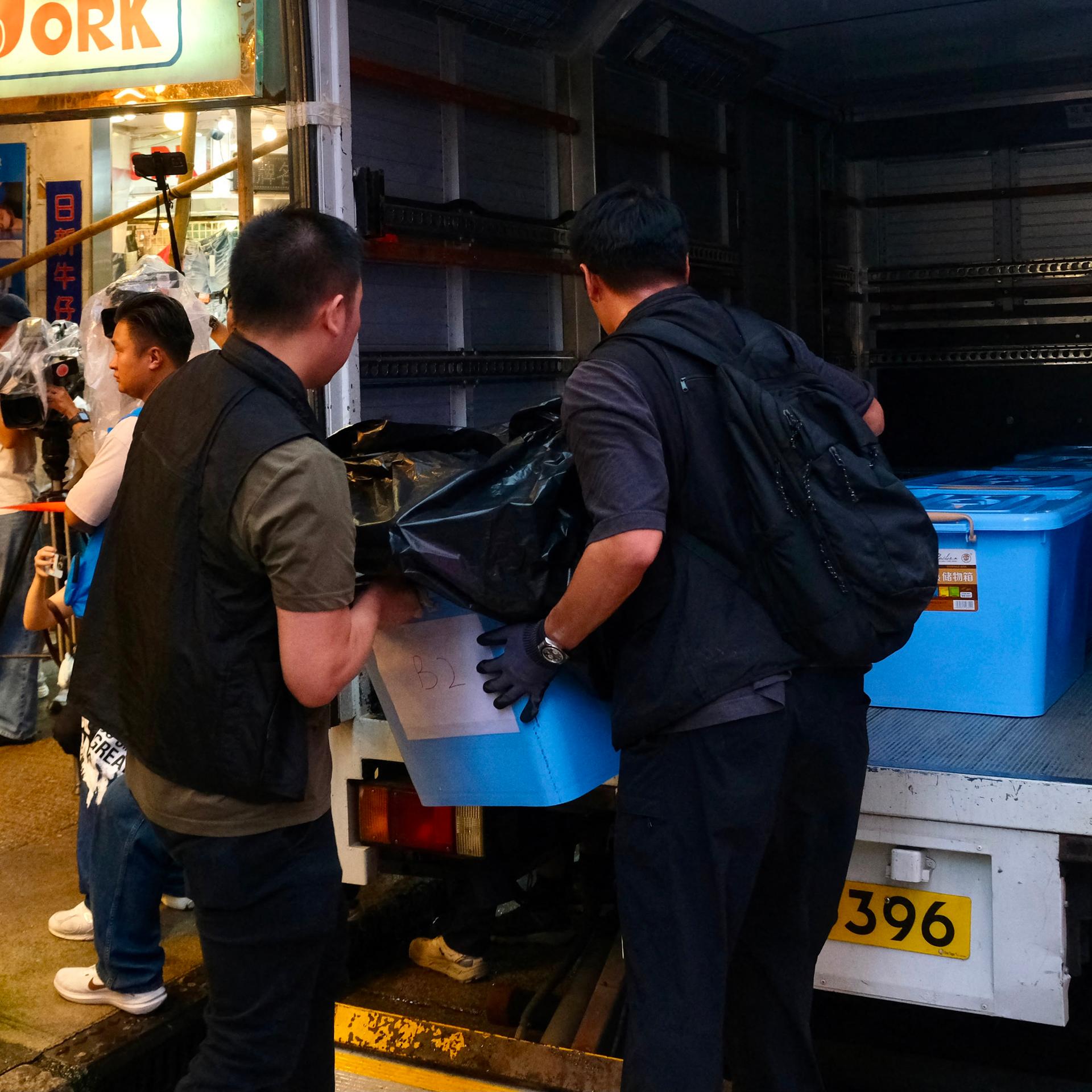 Polizisten laden beschlagnahmtes Material aus einem Buchladen in Hongkong in ihr Auto.