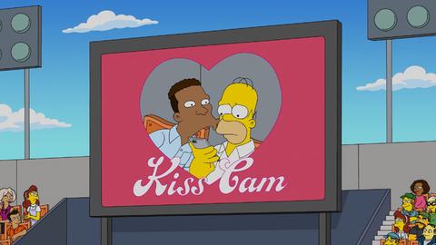 Zu sehen ist eine Leinwand in einem Stadion, unter der "Kiss-Cam" (deutsch: Kuss-Kamera) steht. Homer Simpson bekommt auf der Leinwand einen Kuss von Carl Carlson, schaut aber etwas bedröppelt. 