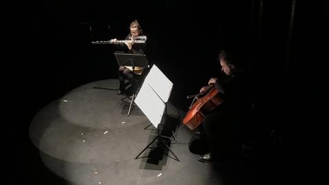 Zwei Musiker sitzen im Scheinwerferkegel auf einer dunklen Bühne