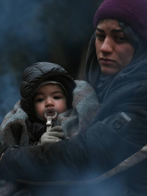 Frau mit Kind wärmt sich am Feuer: Flüchtlinge in Belarus an der Grenze zu Polen.