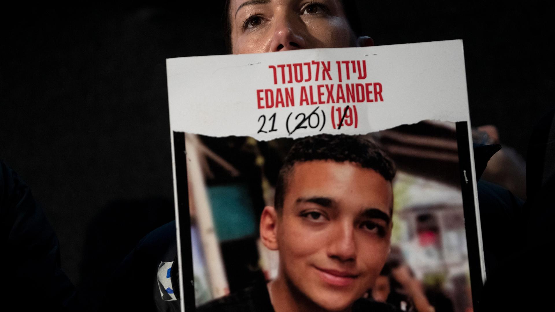 Es ist dunkel. Das Gesicht der Mutter ist hinter dem großen Plakat nur teilweise zu sehen. Es ist dunkel. Das Gesicht der Mutter ist hinter dem großen Plakat nur teilweise zu sehen.