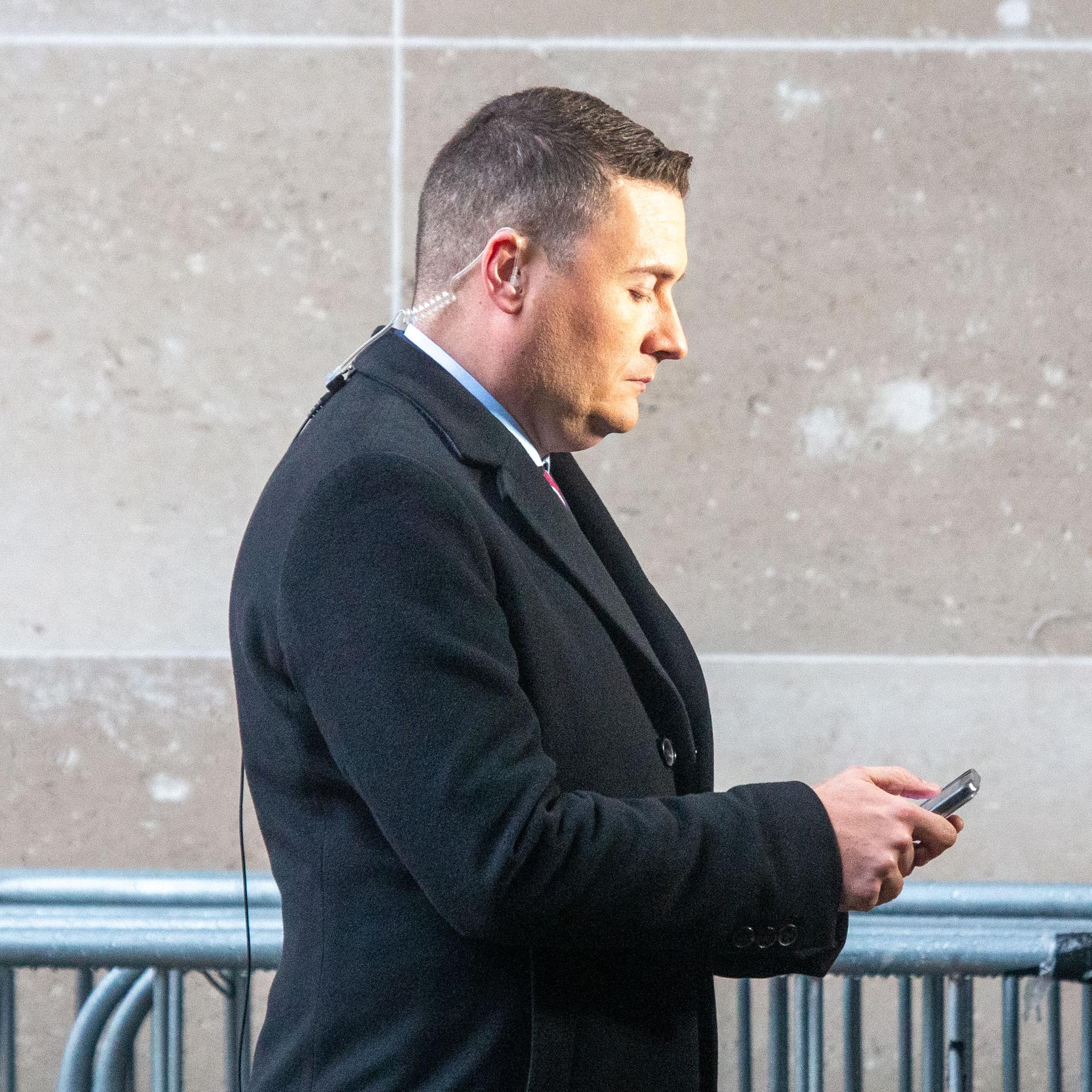 Gesundheitsminister Großbritanniens Wes Streetings im Profil mit Blick auf sein Mobiltelefon.