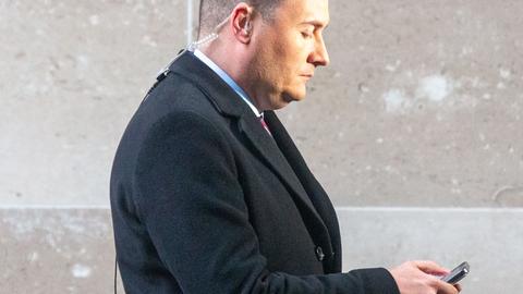 Gesundheitsminister Großbritanniens Wes Streetings im Profil mit Blick auf sein Mobiltelefon.