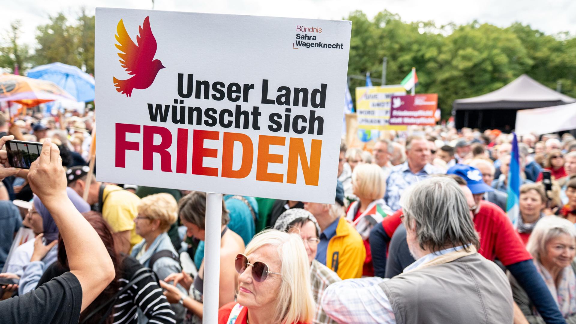 Eine Kundgebungsteilnehmerin hält ein Schild mit der Aufschrift "Unser Land wünscht sich Frieden". Eine Kundgebungsteilnehmerin hält ein Schild mit der Aufschrift "Unser Land wünscht sich Frieden".