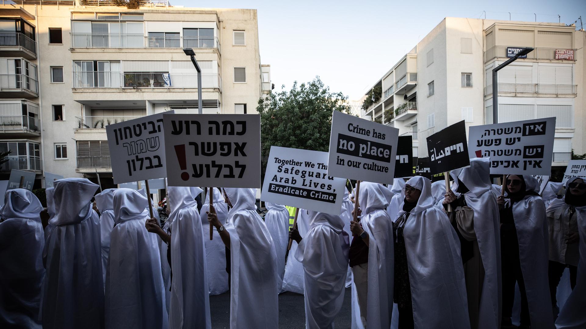Arabische Israelis demonstrieren in weißer Kleidung, mit Schildern und Särgen aus Pappmaché.