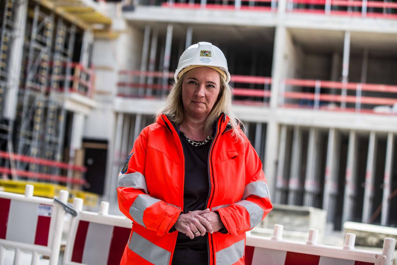 Kerstin Schreyer steht in einer orangefarbenen Warnweste auf einer Baustelle.