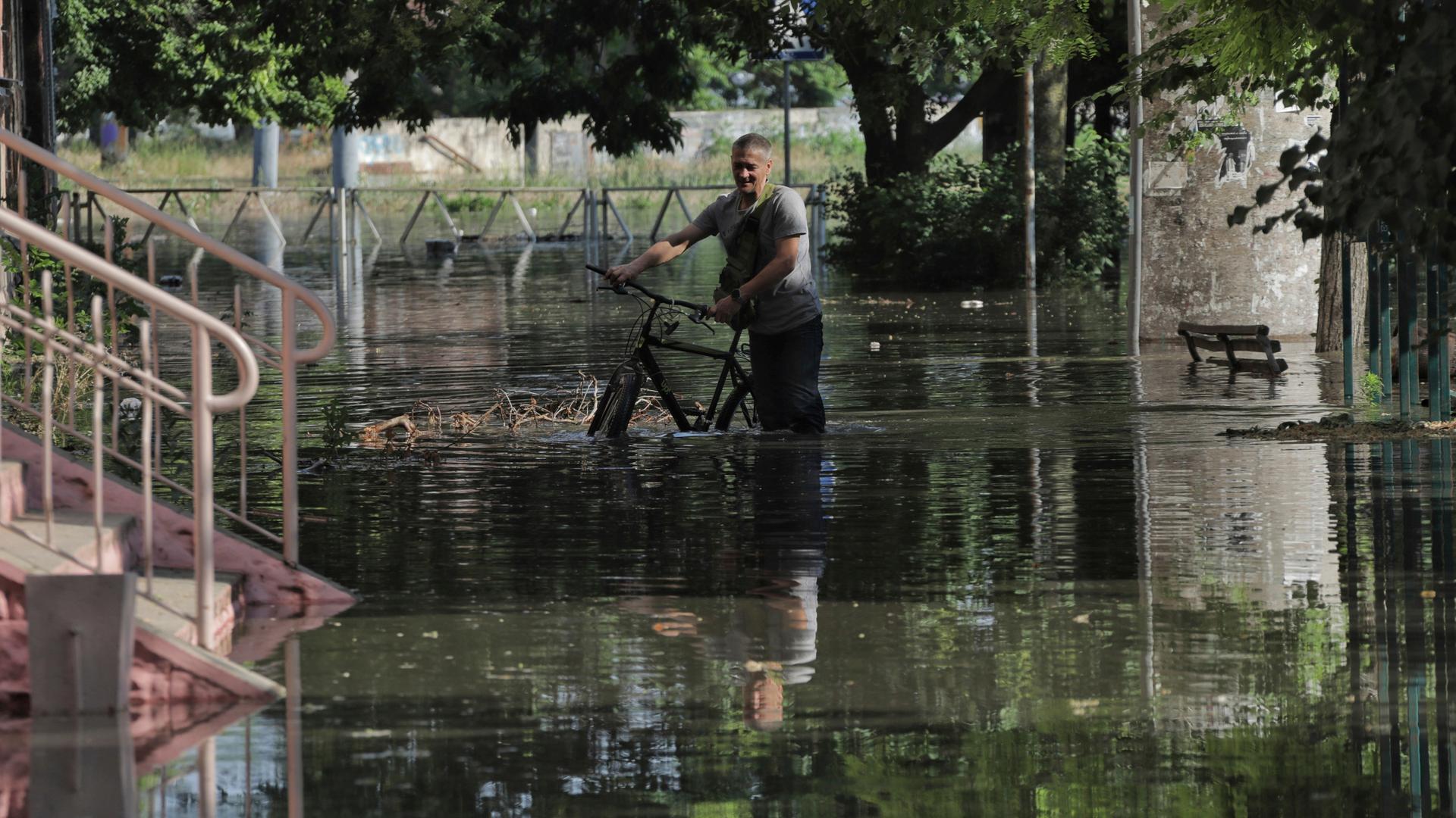 Ein Mann schiebt sein Fahrrad durch knietiefes Wasser. Ein Mann schiebt sein Fahrrad durch knietiefes Wasser.