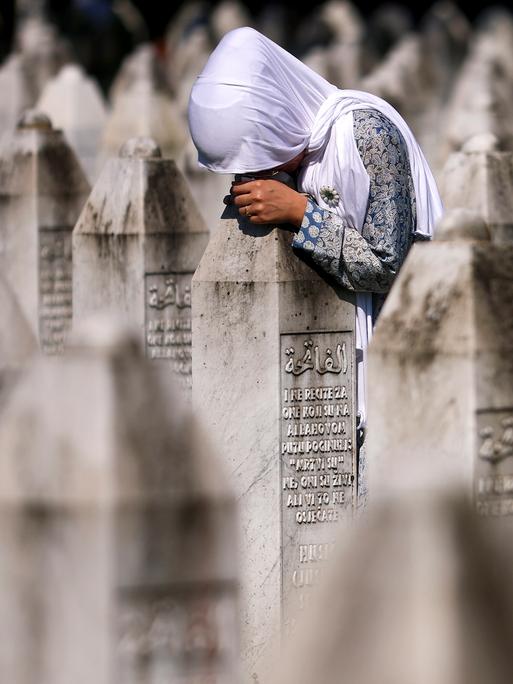 Eine muslimische Frau trauert am Grab ihres Verwandten in der Srebrenica-Gedenkstätte in Potocari, Bosnien.