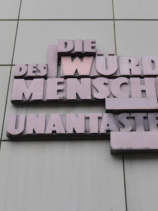 Der Schriftzug "Die Würde des Menschen ist unantastbar" steht in Großbuchstaben aus Metall an einem Gerichtsgebäude in Frankfurt am Main.