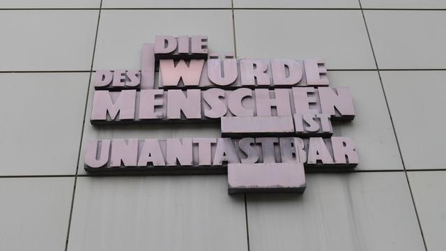 Der Schriftzug "Die Würde des Menschen ist unantastbar" steht in Großbuchstaben aus Metall an einem Gerichtsgebäude in Frankfurt am Main.