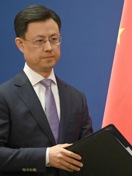 Ein ernst blickender Mann in Anzug steht neben einer chinesischen Flagge: Chinas Außenamtssprecher Guo Jiakun äußert sich zum Iran-Krieg. Ein ernst blickender Mann in Anzug steht neben einer chinesischen Flagge: Chinas Außenamtssprecher Guo Jiakun äußert sich zum Iran-Krieg.