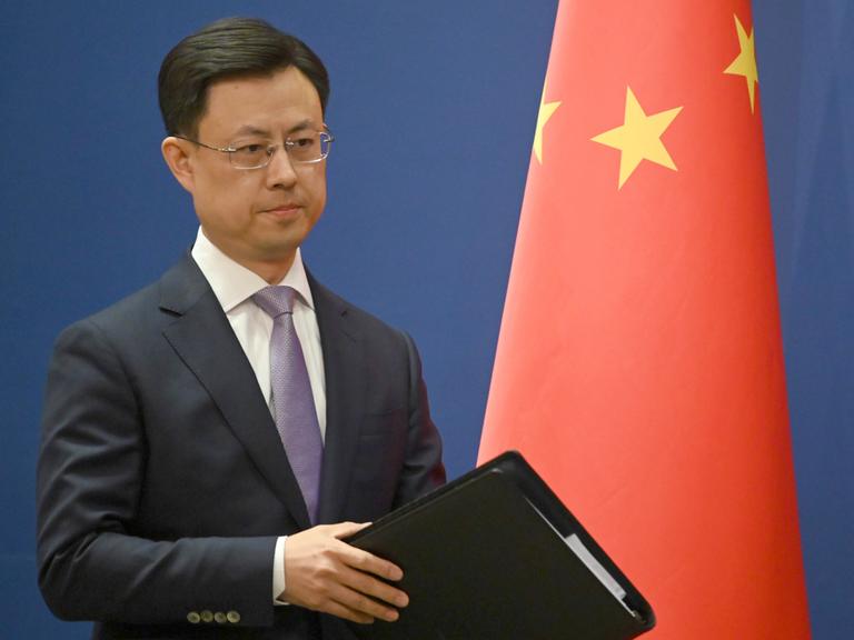 Ein ernst blickender Mann in Anzug steht neben einer chinesischen Flagge: Chinas Außenamtssprecher Guo Jiakun äußert sich zum Iran-Krieg. Ein ernst blickender Mann in Anzug steht neben einer chinesischen Flagge: Chinas Außenamtssprecher Guo Jiakun äußert sich zum Iran-Krieg.