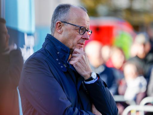 Bundeskanzler Friedrich Merz (CDU) steht mit einer Jacke draußen und hört sich beim Bürgergespräch Fragen der Zuschauer an.