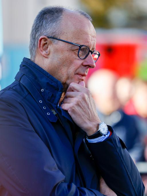 Bundeskanzler Friedrich Merz (CDU) steht mit einer Jacke draußen und hört sich beim Bürgergespräch Fragen der Zuschauer an.