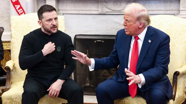 Der ukrainische Präsident Selenskyj und der Präsident der USA, Trump, sitzen nebeneinander. Selenskyj zeigt mit der Hand auf sich selbst. Trump redet und gestikuliert mit beiden Händen. 