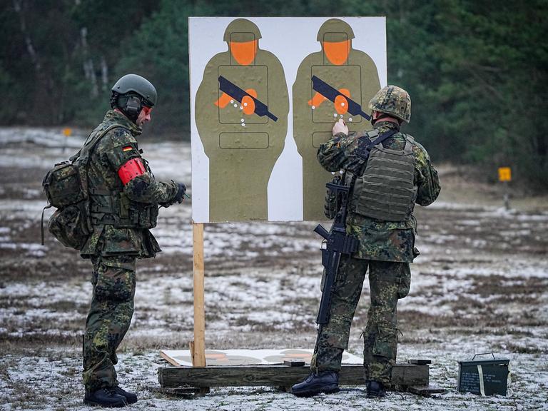 Zwei Bundeswehrsoldaten trainieren mit dem G36-Gewehr auf einem Truppenübungsplatz mit Pappsoldaten als Zielscheibe. 