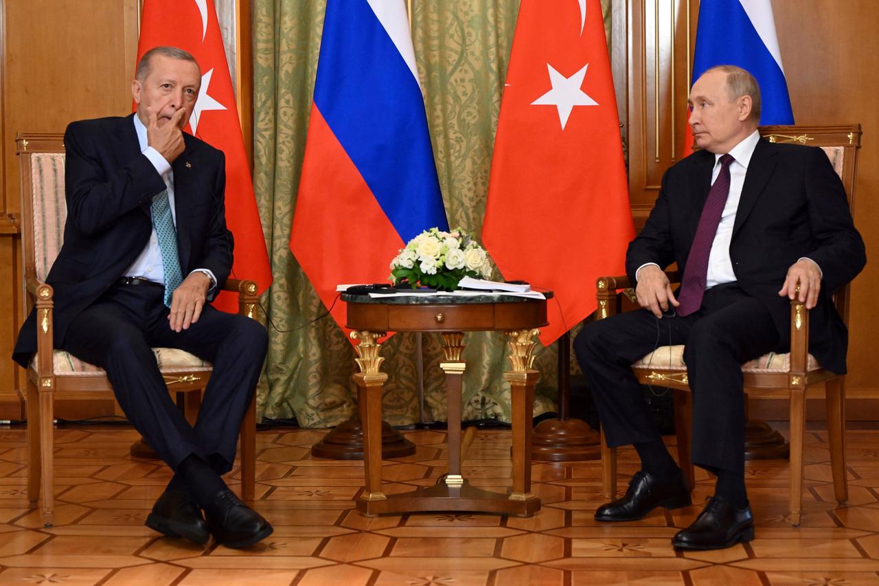 Die Präsidenten Erdogan und Putin sitzen sich an einem Tisch gegenüber, dazwischen eine türkische und russische Flagge.