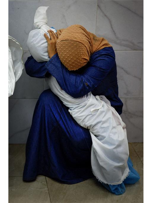 Das "World Press Photo" des Jahres: Das Foto zeigt Ina Abu Maamar, die ein blaues Kleid und ein ockerfarbenes Kopftuch trägt. Sie beugt sich über den in ein weißes Laken gehüllten Leichnam ihrer fünf Jahre alten Nichte Saly
