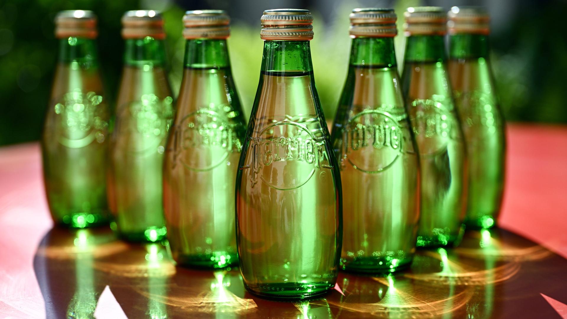 Mehrere grüne Glasflaschen mit dem Logo des französischen Trinkwassermarke Perrier.