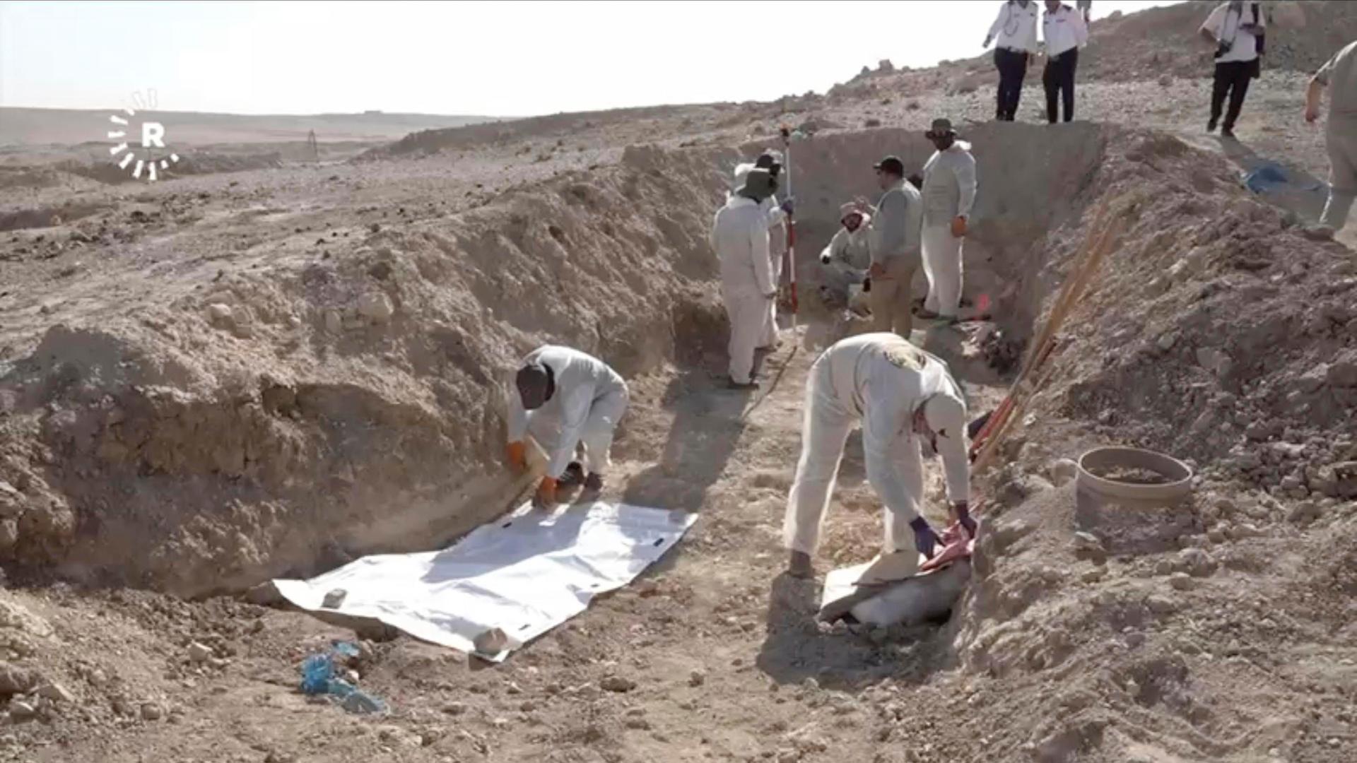 Arbeiter graben menschliche Überreste in der Nähe der nordirakischen Stadt Mosul aus. Arbeiter graben menschliche Überreste in der Nähe der nordirakischen Stadt Mosul aus.