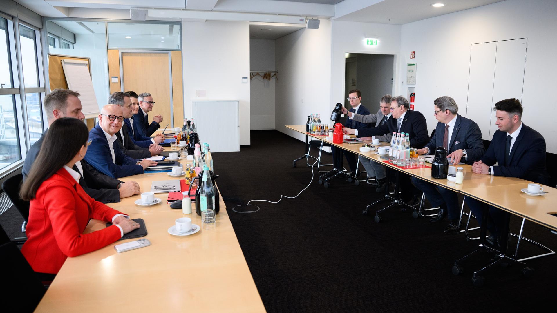 Die beiden Tarifparteien sitzen sich in einem relativ kleinen Raum an Tischen gegenüber. Man sieht sie von der Seite. 