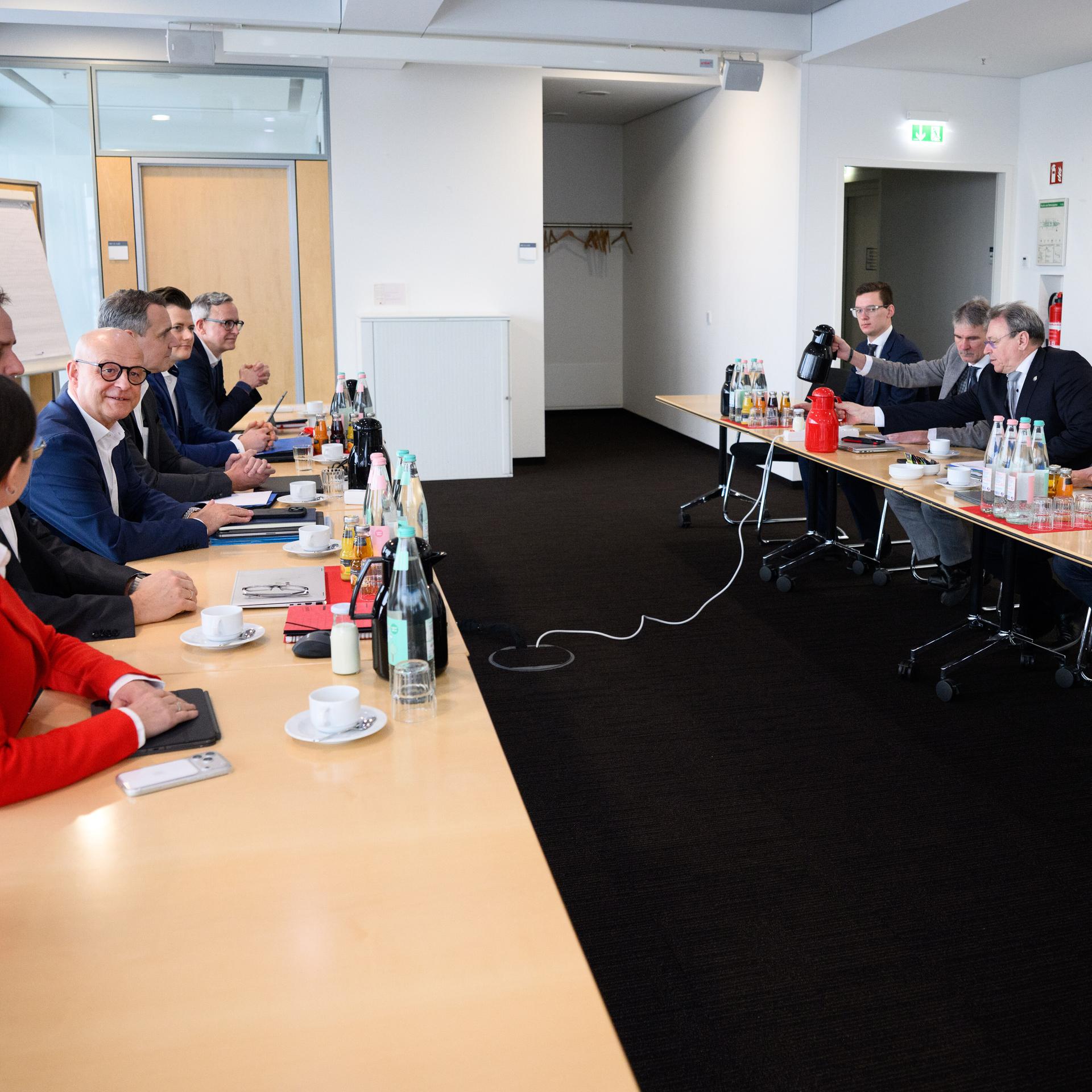 Die beiden Tarifparteien sitzen sich in einem relativ kleinen Raum an Tischen gegenüber. Man sieht sie von der Seite. 