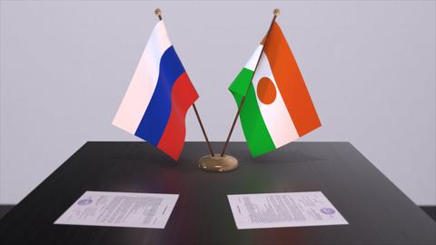Die Nationalflaggen Russlands und Nigers stehen auf einem Tisch nebeneinander. 