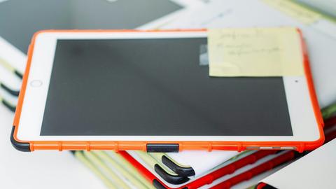 Ein Stapel von Ipads in bunten Hüllen liegt auf einem Schreibtisch