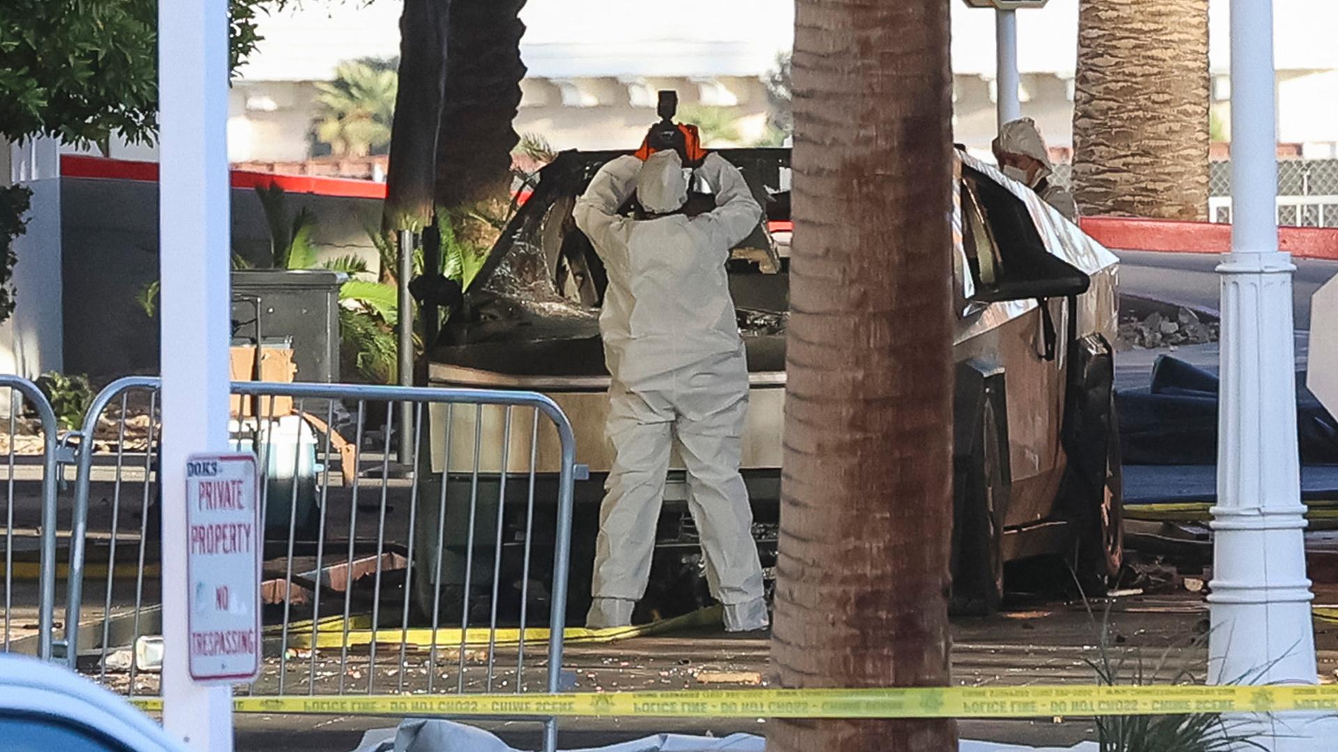 Ein Polizei-Mitarbeiter fotografiert den explodierten Tesla-Wagen.