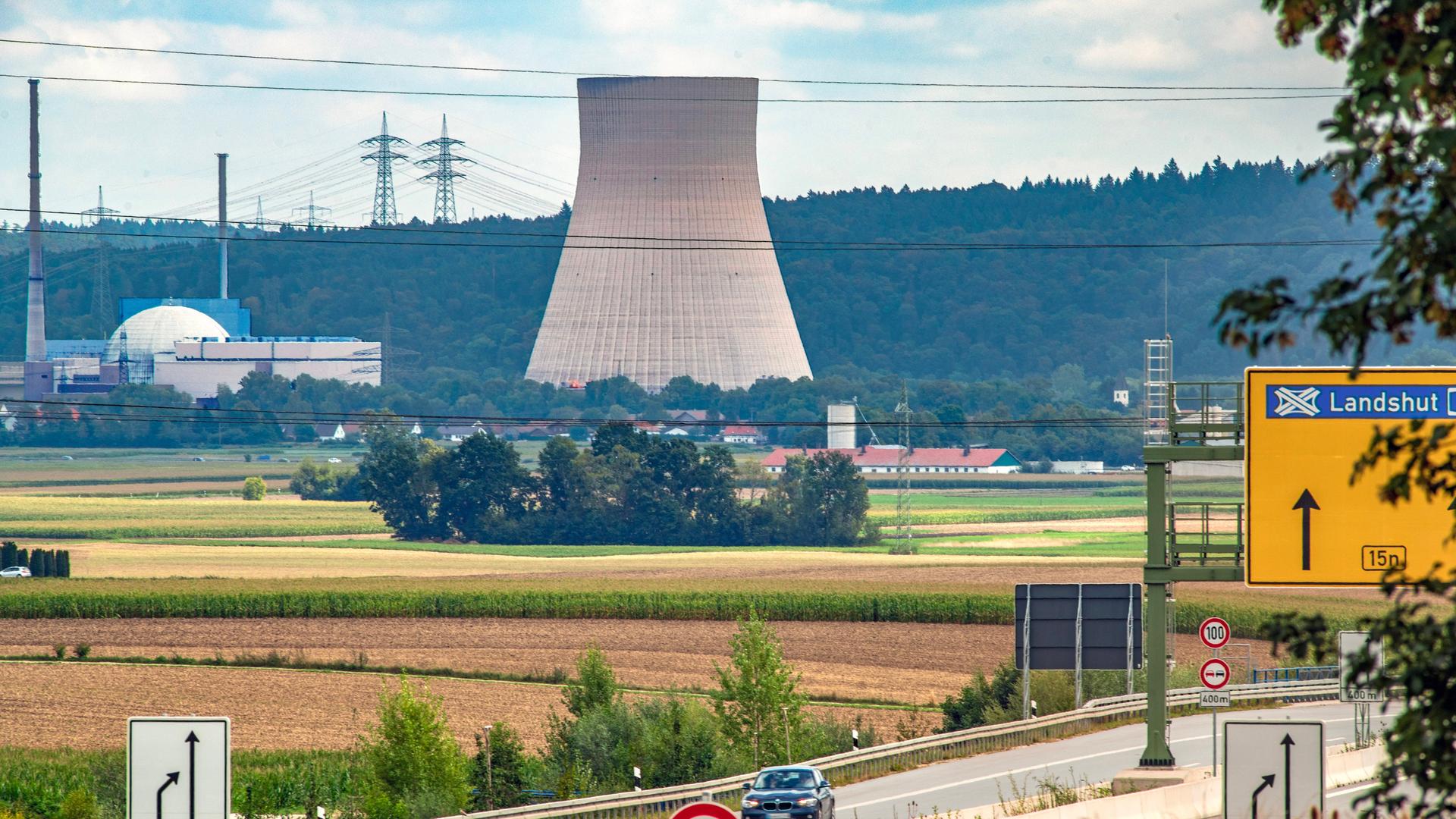 Aus dem Kühlturm des abgeschalteten Atomkraftwerks Isar 2 kommt kein Wasserdampf mehr. Man sieht im Vordergrund eine Autobahn.