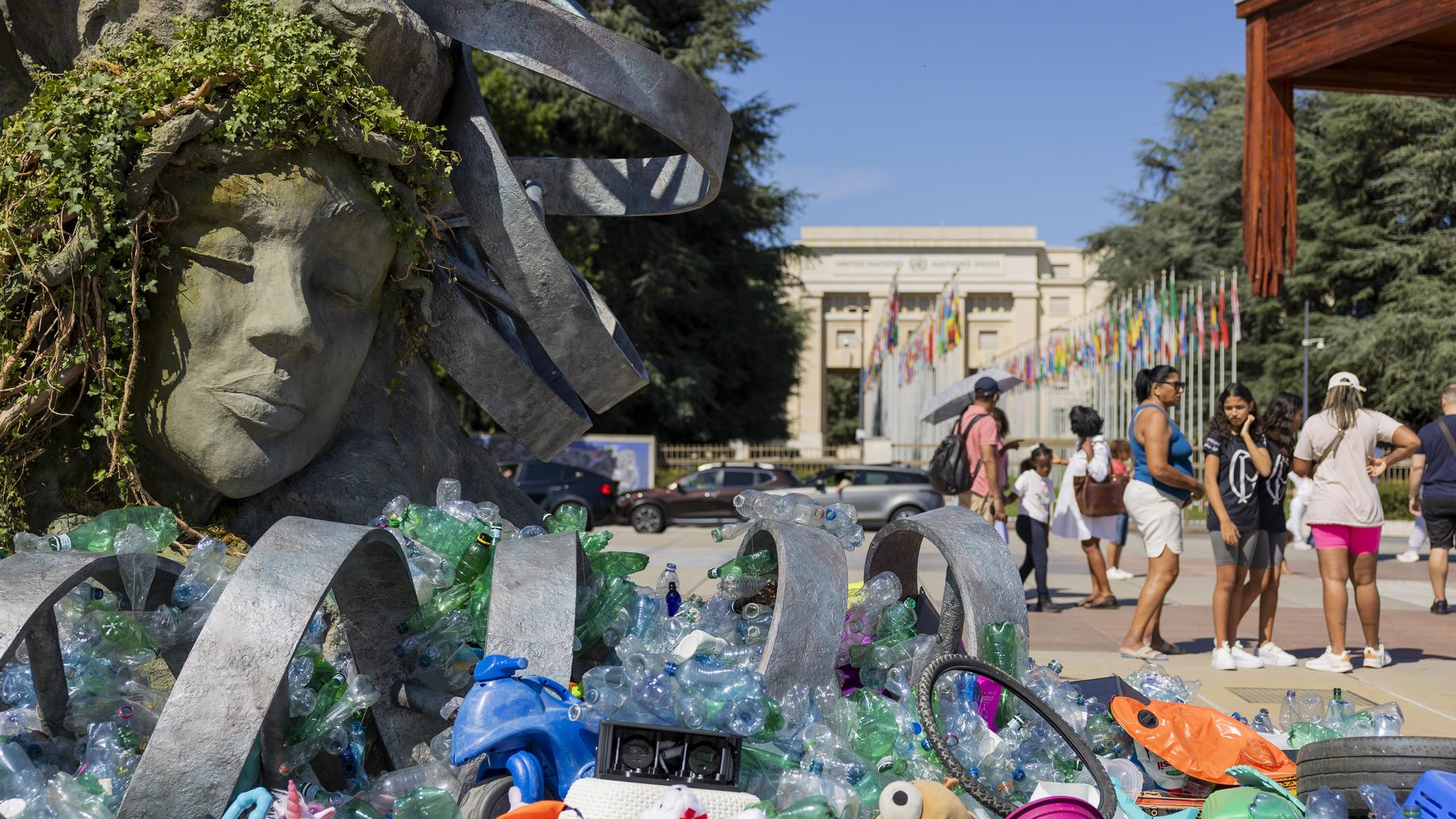 Vor dem UN-Hauptsitz in Genf steht eine sechs Meter hohe Skulptur von Benjamin Von Wong: eine Neuinterpretation von Rodins „Denker“, beladen mit gesammelten Plastikteilen. Im Vordergrund liegen weitere Plastikgegenstände.