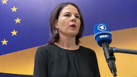 Außenministerin Baerbock spricht an einem Mikrofon.