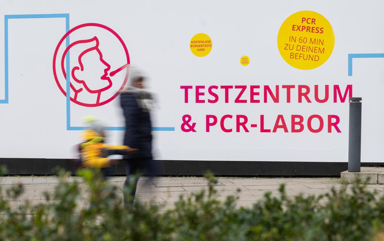 Eine Frau und ein Kind laufen in Hannover an einem Testzentrum für das Corona-Virus vorbei