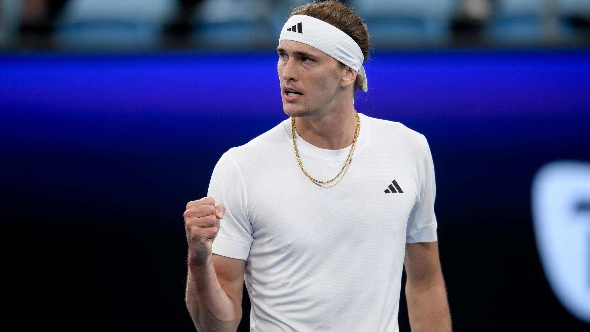 Tennisprofi Alexander Zverev auf dem Platz beim United Cup in Sydney. Er trägt ein weißes T-Shirt und ein Stirnband und ballt die rechte Hand zu einer Faust.
