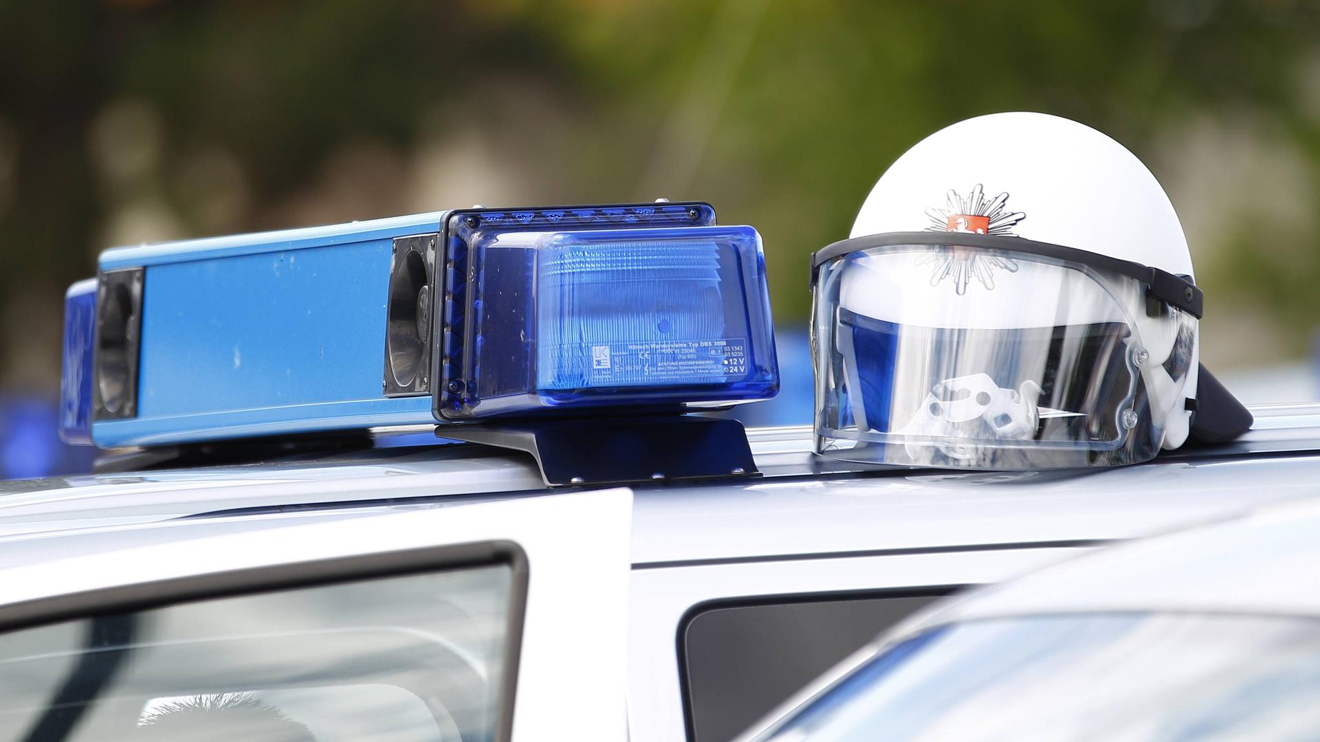 Auf dem Dach eines Polizeiautos mit Blaulichtanlage liegt ein Schutzhelm.