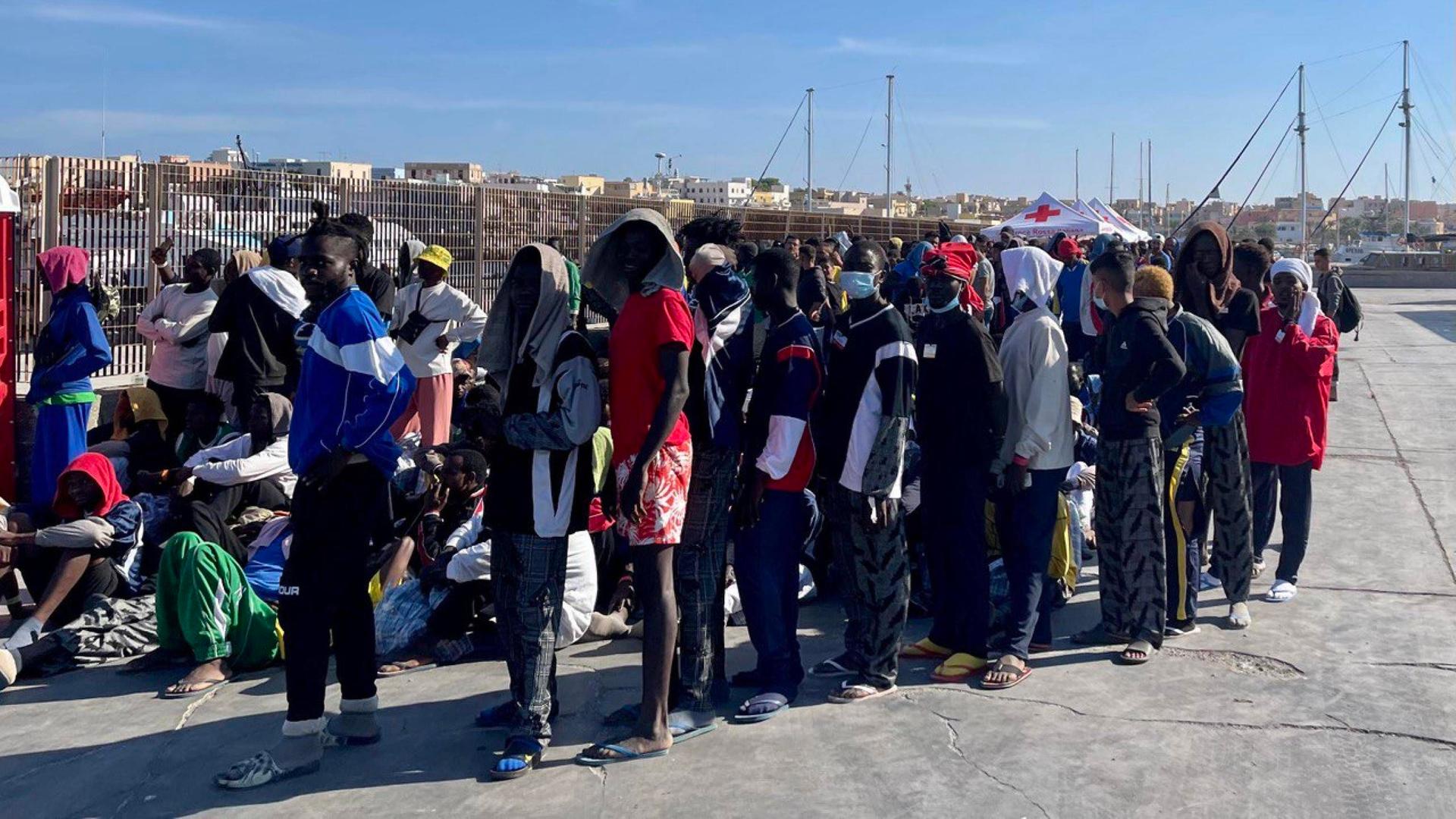 Migranten erreichen die Insel Lampedusa und warten in einer Schlange.